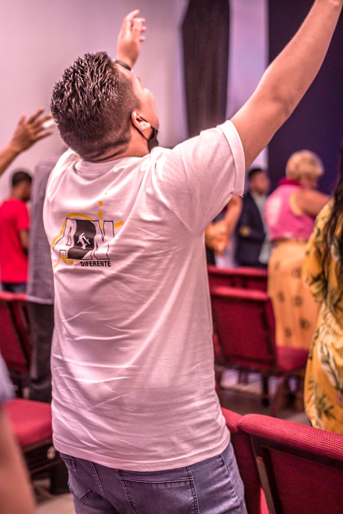 A man raising his hands in prayer during a church service, expressing devotion.