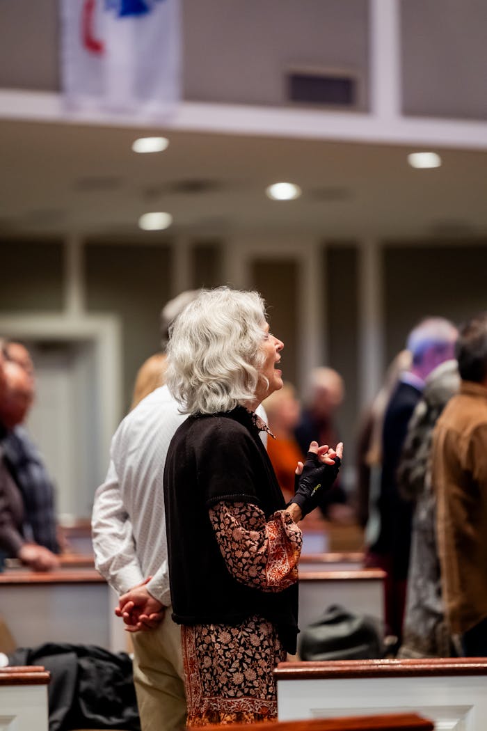 The Art of Drawing Readers In: Your attractive post title goes here Senior woman singing during a church service with a diverse congregation in attendance.